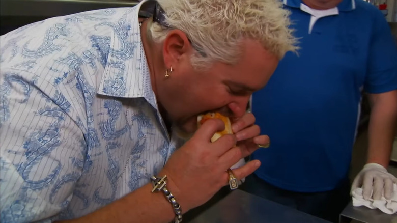Guy Fieri leaning over to bite into meatball sub on episode of Diners, Drive-Ins and Dives at Steer-In