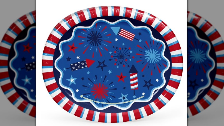 Oval red, white, and blue paper plate decorated with fireworks, flags, rockets, and stars