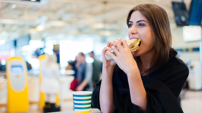 woman in airport eating sandwich