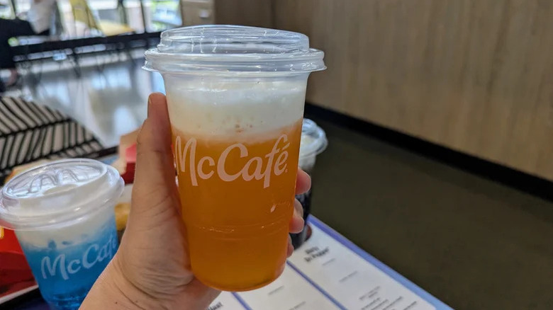 Person holding new orange dream drink in McCafe cup