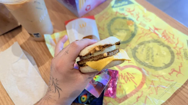 person holding McDonald's breakfast sandwich with sauce