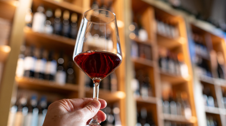 Someone hold a glass of red wine up in the air