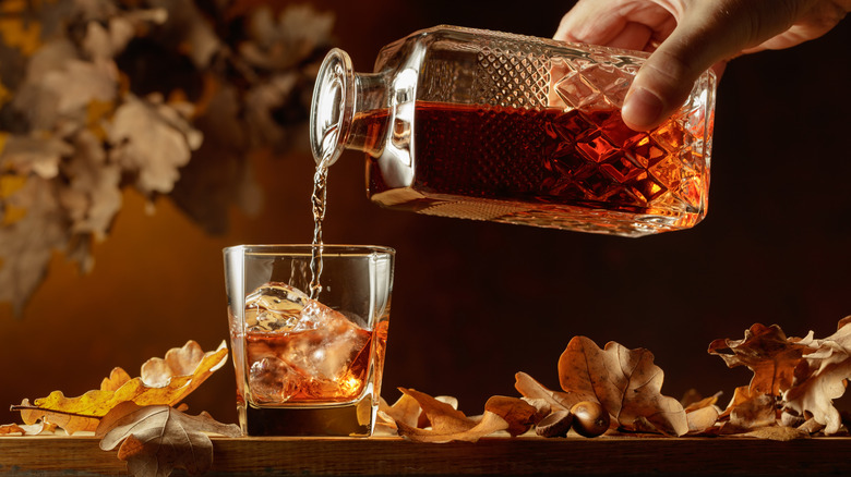 hand pouring whiskey from crystal decanter