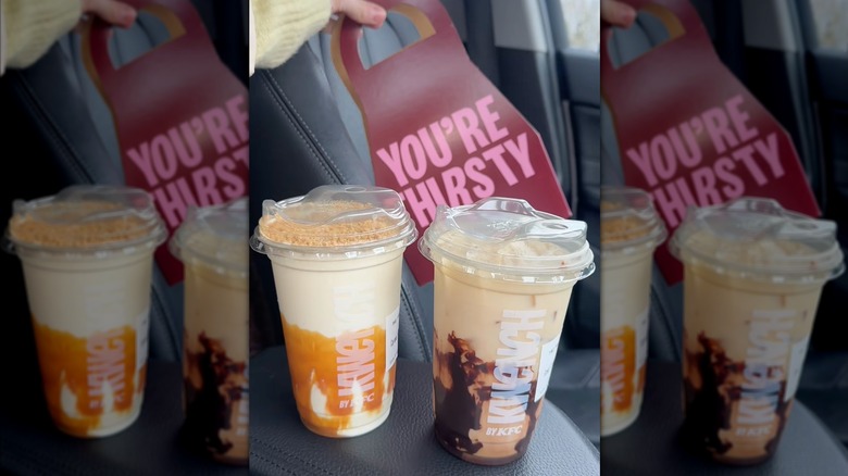 Two KFC Kwench coffee drinks with caramel and chocolate syrups in plastic takeout cups in car