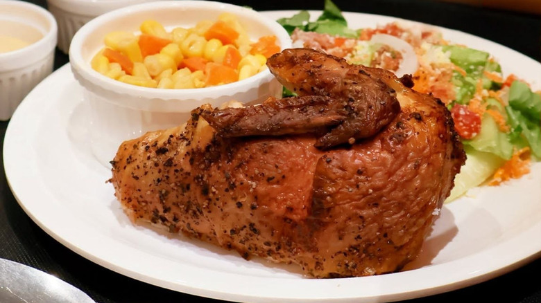 White plate with rotisserie chicken and sides