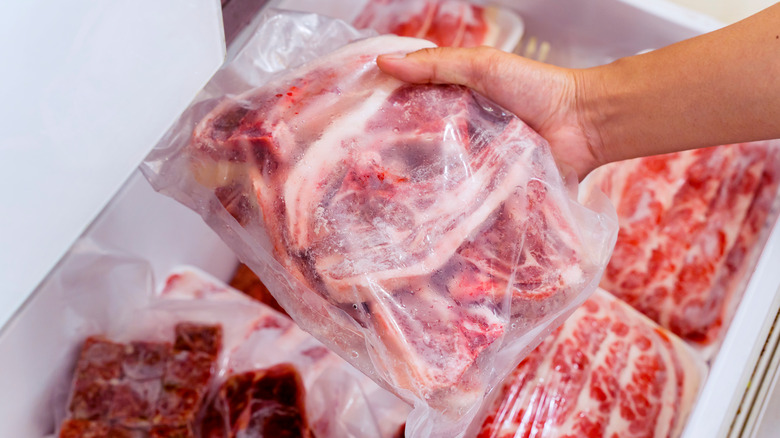 person picking up bag of frozen meat