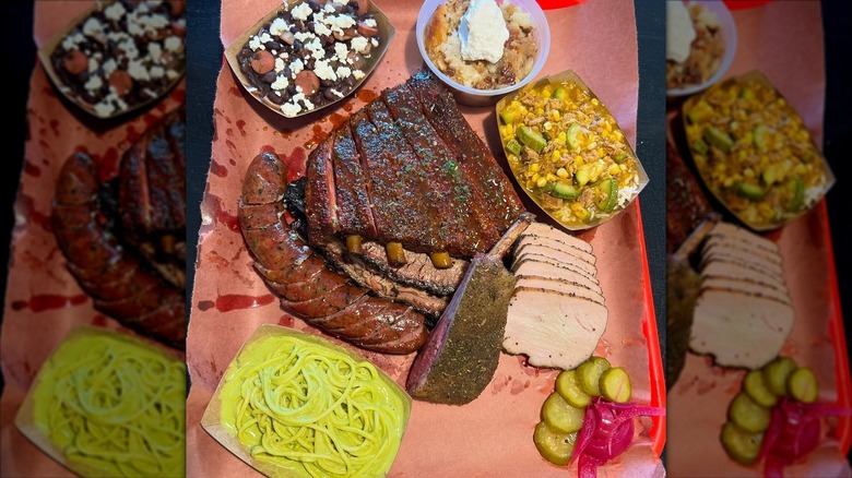 an array of barbecue meats surrounded by side dishes