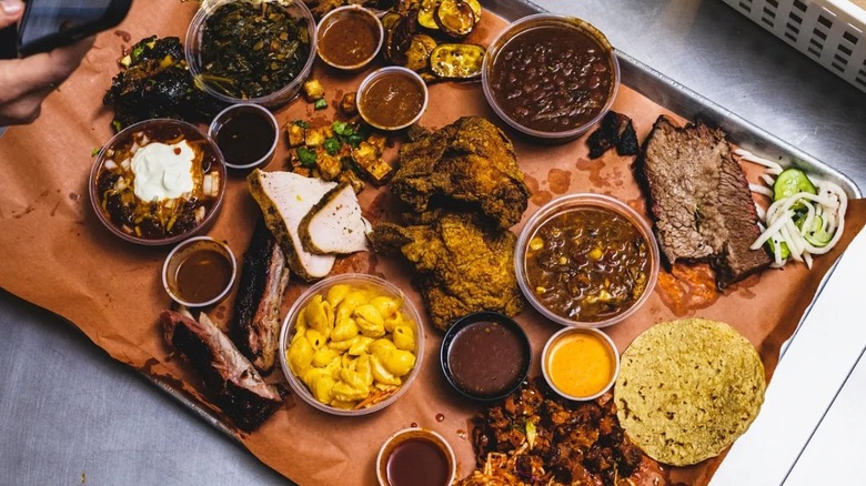 A large tray full of barbecue and slides including mac and cheese, chili, Korean pickled veggies, and a tortilla