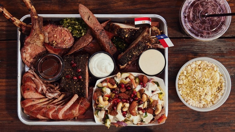 An overhead shot of mixed barbecue and sides decorated with tiny Texas and Egypt flags
