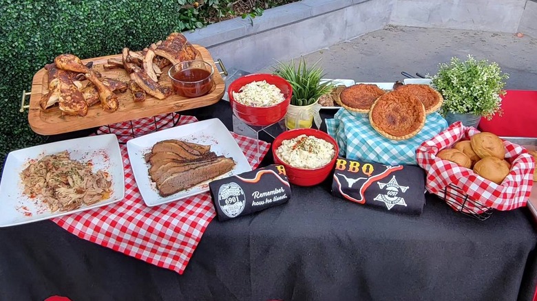 A table lined with barbecue, sides, pies, and rolls