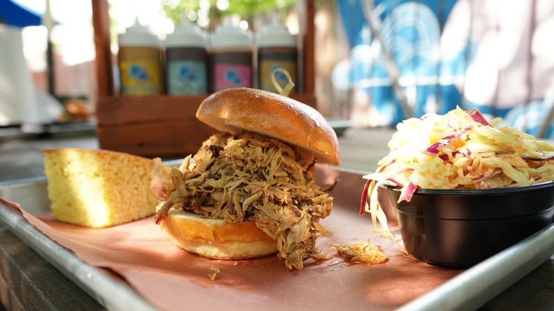 A tray with a barbecue sandwich, corn bread, and coleslaw