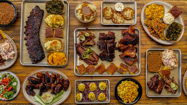 A collection of plates and platters with barbecue and sides