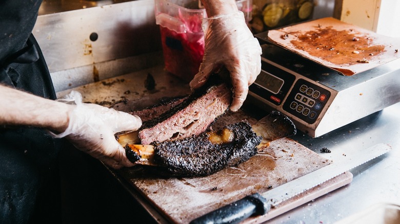 hands holding a rack of ribs above a cutting board