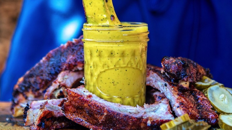 A cup of sauce surrounded by ribs
