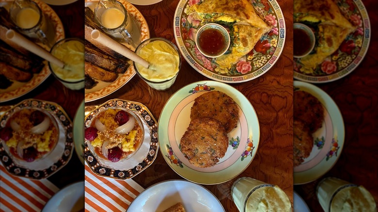 Assorted plates with breakfast sandwich and sauce, a smoothie, toast