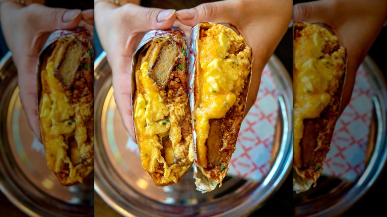 Hands holding a breakfast sandwich split in two