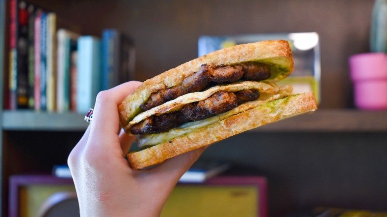 A hand holding a breakfast sandwich