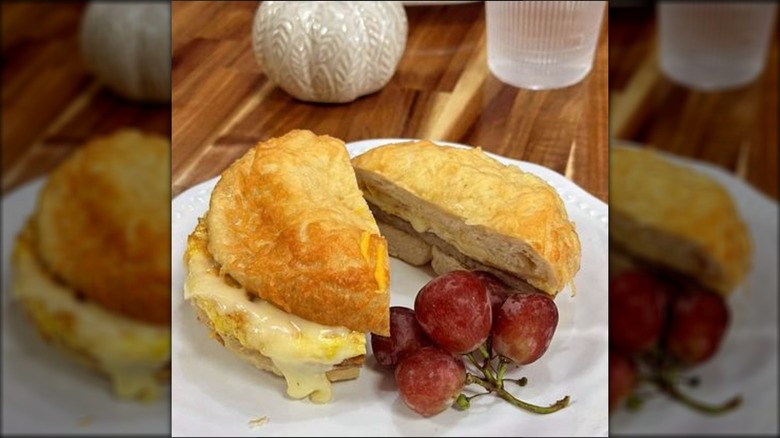 Sandwich split in two with a handful of grapes on a plate