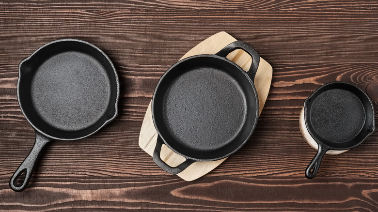 three cast iron skillets on a wooden table