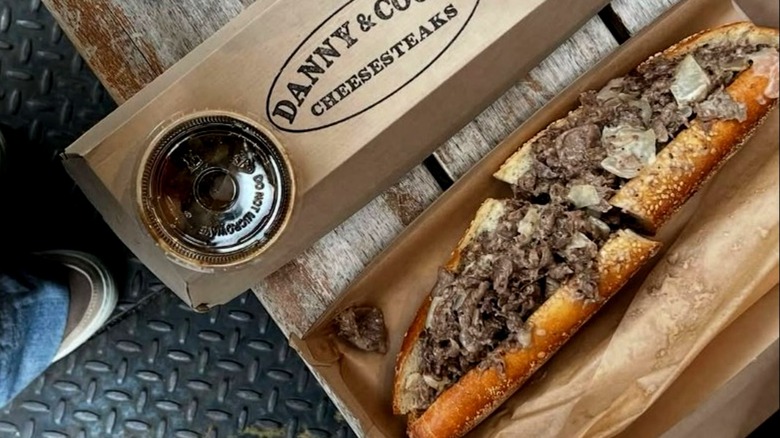 Danny and Coops cheesesteak in box with side of dipping sauce