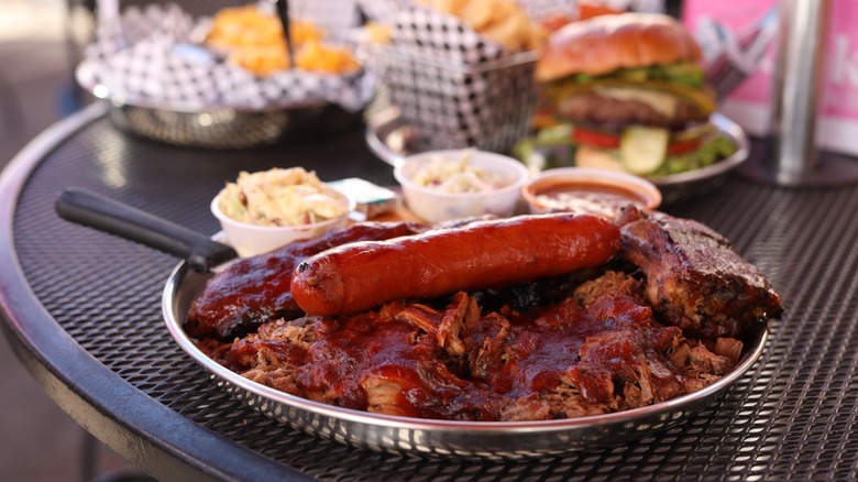 Plate of barbecue with hot dog and sides on outdoor table