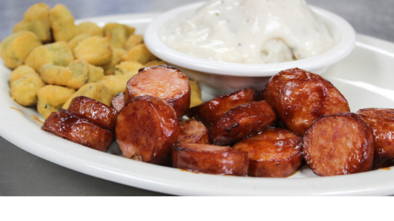 Plate of sliced sausage, fried veggies, and mashed potatoes with gravy