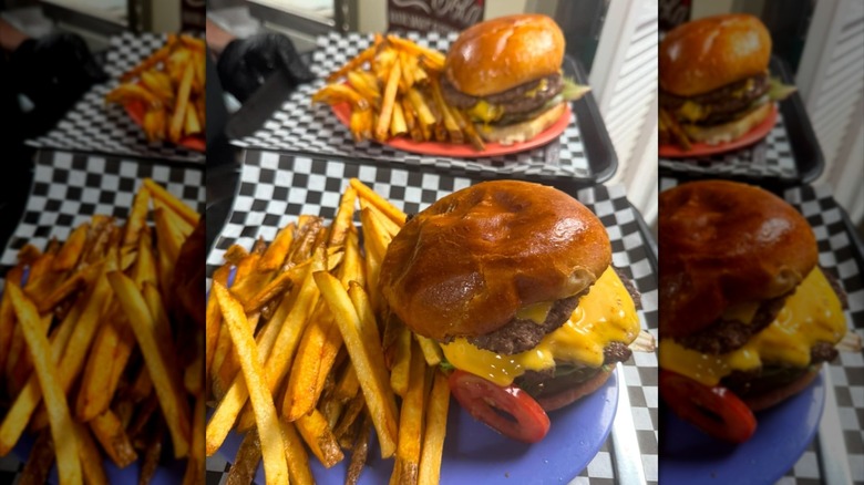 Two burgers with fries on trays lined with checkered paper