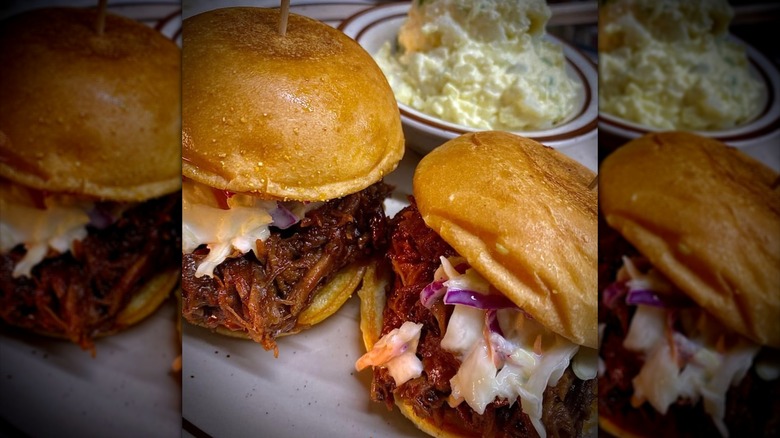 Two pulled pork sandwiches with slaw and side of potato salad