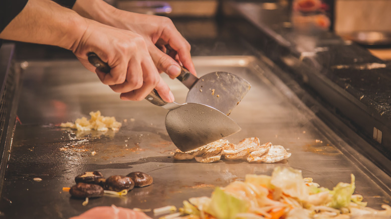 A chef cooks food on a hibachi grill