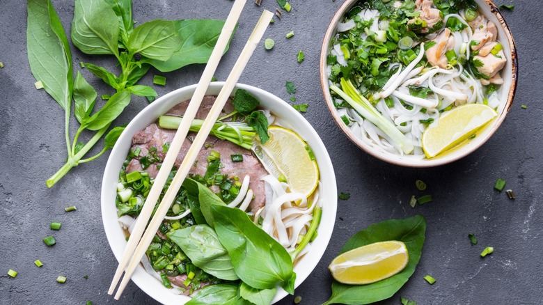 Beef and chicken pho with sprigs of basil and lemon