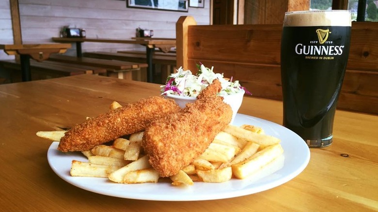Fish and chips with slaw and a pint of Guinness on a restaurant table