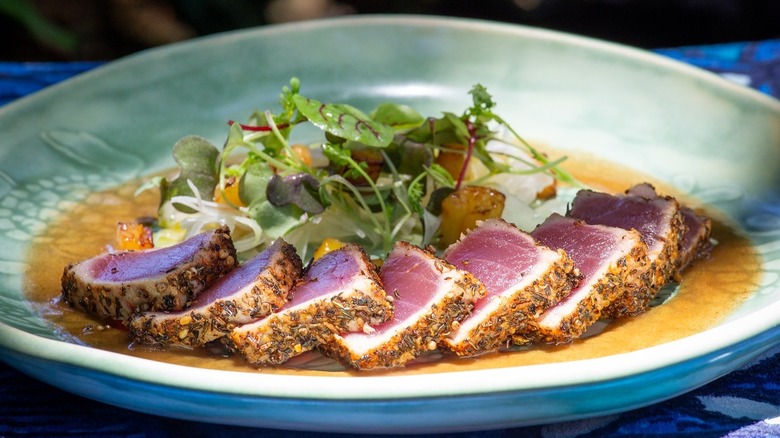 Seared ahi tuna plated with sauce and microgreens