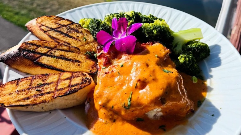 a dish with a seafood patty with sauce, broccoli and potato