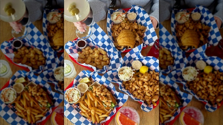 overhead shot of a table full of fried seafood dishes, one hand raising a martini