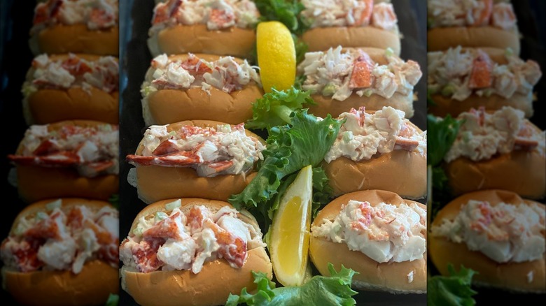 Mini lobster rolls on a platter with lemon wedges