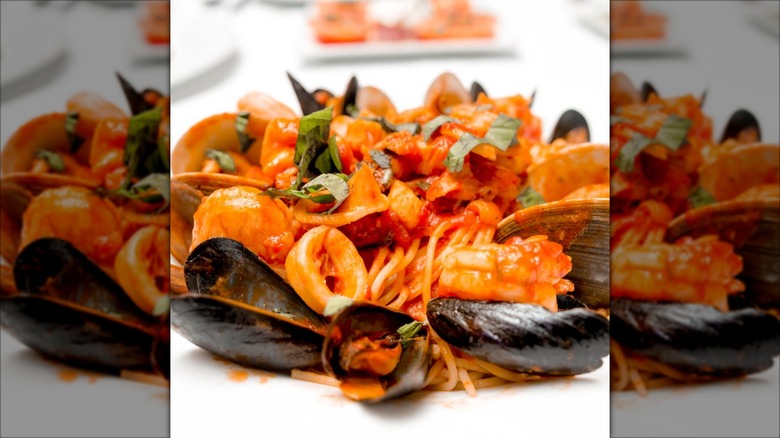 A close-up of seafood pasta featuring mussels, calamari, shrimp and clams in red sauce