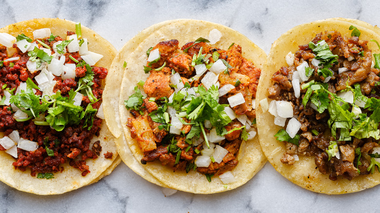 row of mexican street tacos with carne asada al pastor wide banner composition