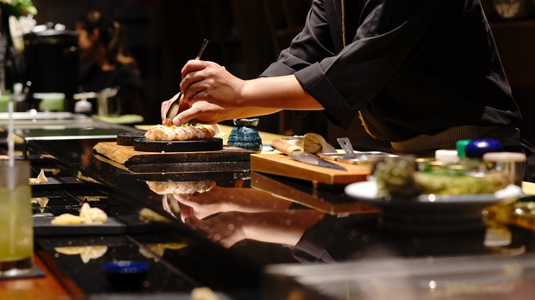 Chef's hands preparing sushi at a counter