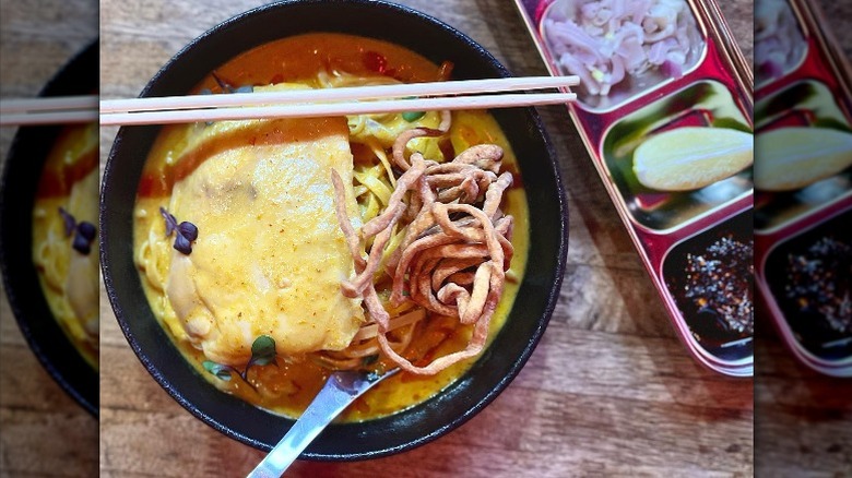 A bowl of soup with egg and side dishes