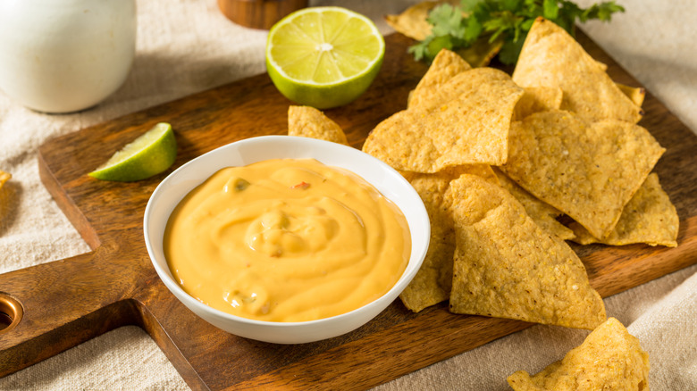 Tortilla chips and bowl of queso on cutting board