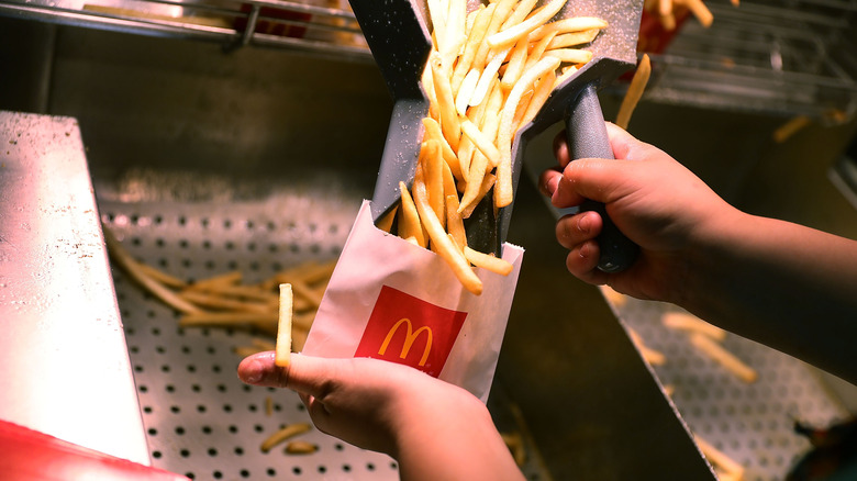 Employee scooping McDonald's French fries into wrapper