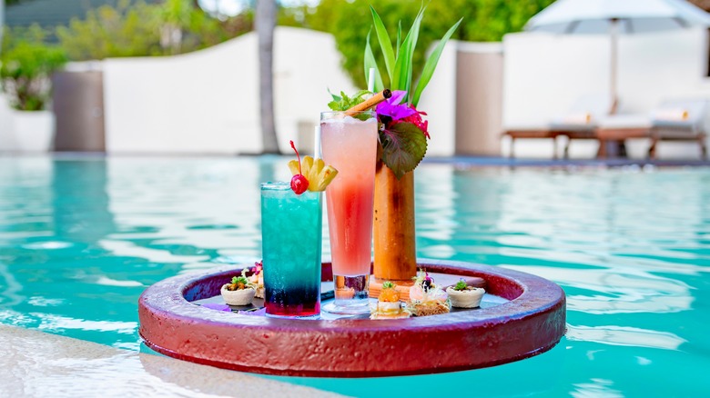 Colorful cocktails on a tray in a pool