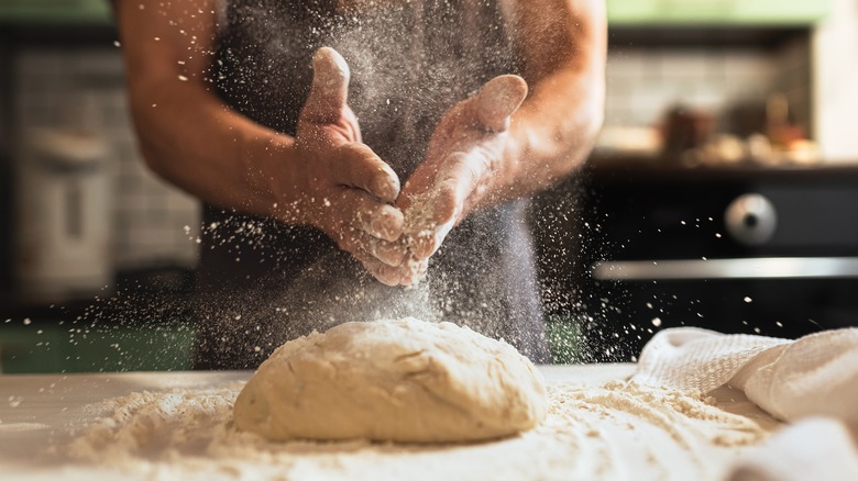 man dusting flour over dough