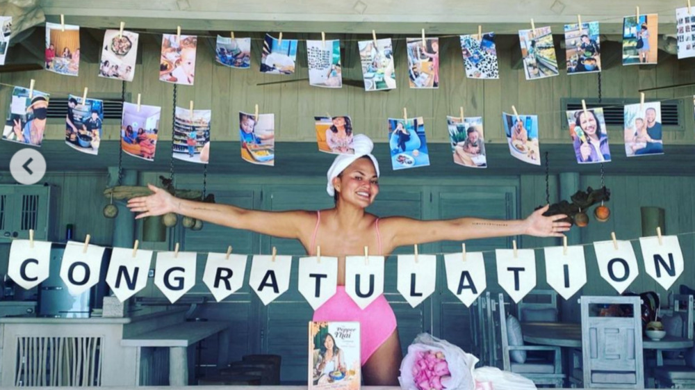 Chrissy Teigen spreading arms and smiling