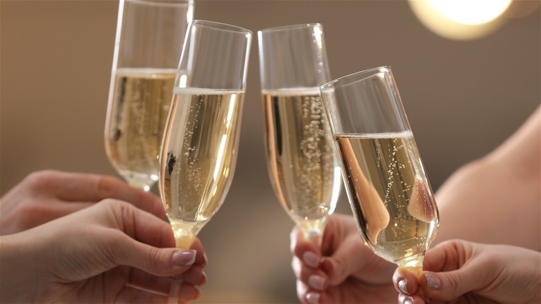 Four people clinking champagne glasses