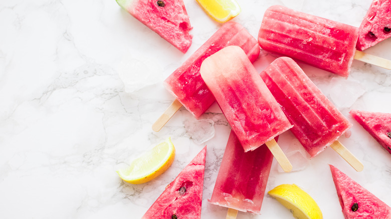 Watermelon popsicles and lemon slices on marble countertop