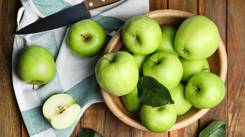 bowl of Granny Smith apples with a knife and a napkin