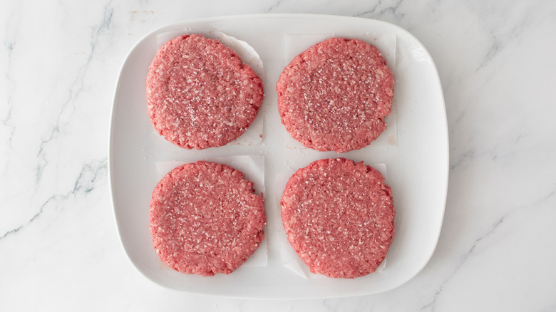 Raw burger patties on plate