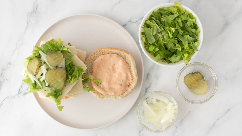 Open burger with lettuce, onion, and pickle toppings
