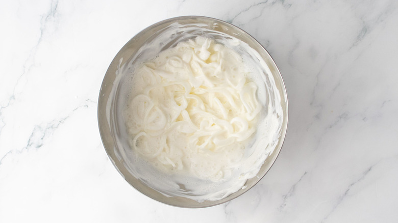Sliced onions coated in buttermilk in bowl